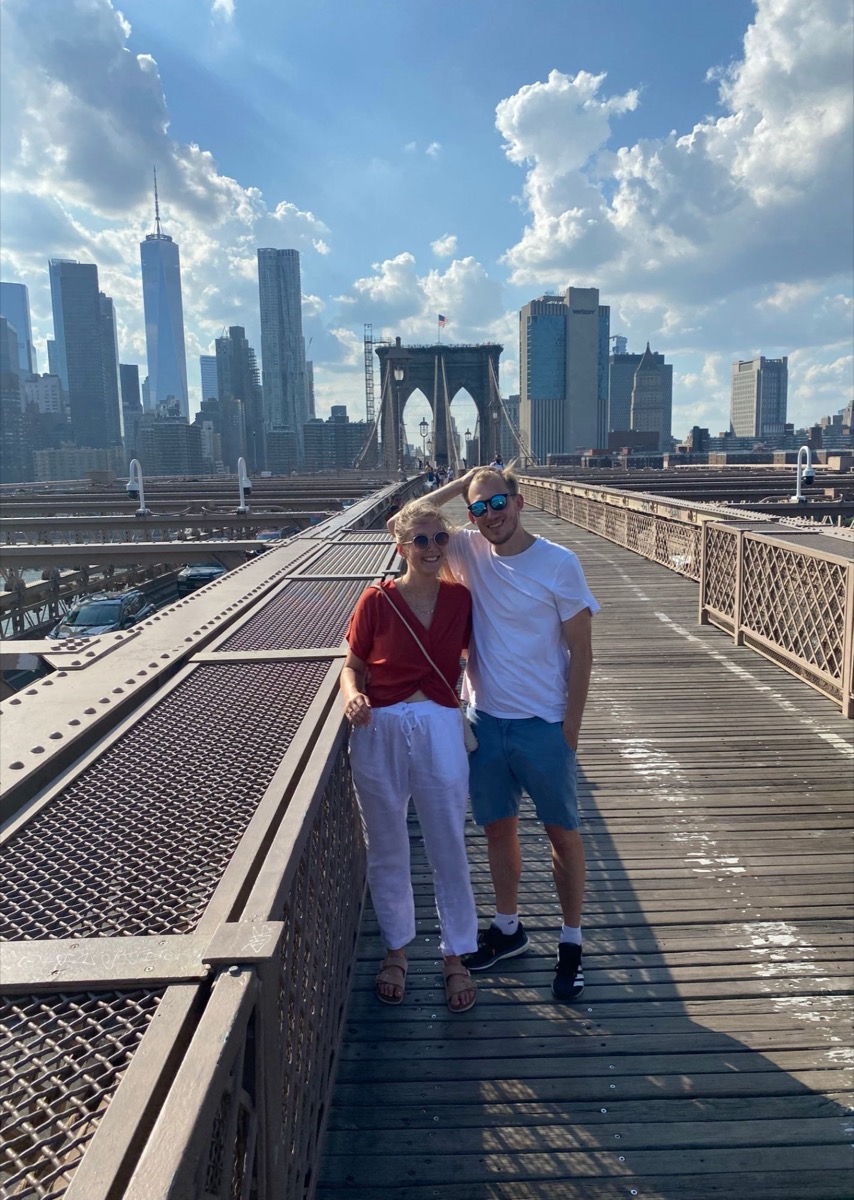 Patricia and Nikolas on the Brooklyn Bridge with the Manhattan skyline behind them